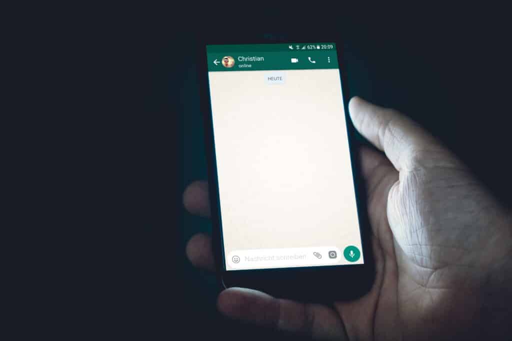 A hand holding a smartphone with WhatsApp online notification activated on it.