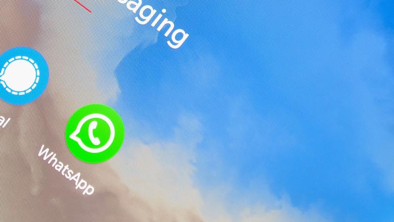 A close-up of a digital screen displaying the WhatsApp application icon mid-download on a cloudy sky background, with "Archived Chats" highlighted as an option to find.